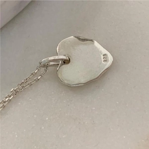 Close-up of heart pendant necklace showing authentic 925 sterling silver hallmark