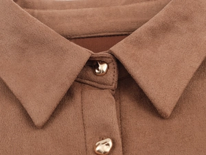 Close-up of golden buttons and textured suede fabric on a camel shirt dress collar