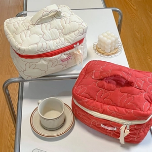 Detailed close-up of quilted cotton cosmetic bags with rabbit patterns and ribbon zippers
