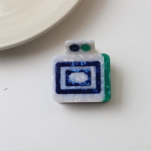Close-up of a rectangular marble-textured acetate hair claw clip with blue geometric pattern