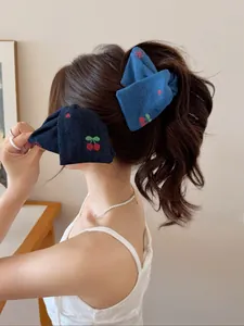 Gros plan sur des pinces à cheveux en jean bleu avec broderie cerise sur mannequin
