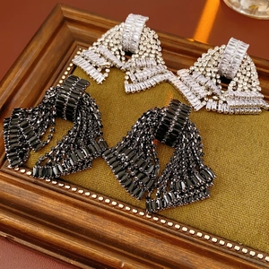 Sparkling rhinestone bow tassel drop earrings in silver and black on green fabric