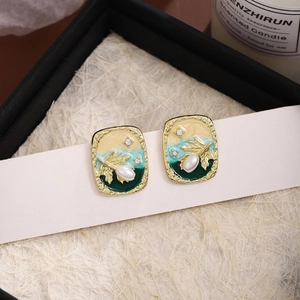 Macro detail of French vintage enamel earrings with pearls and gold wheat leaf accents