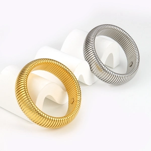 Detailed view of elastic titanium steel bangles in gold and silver on geometric stand