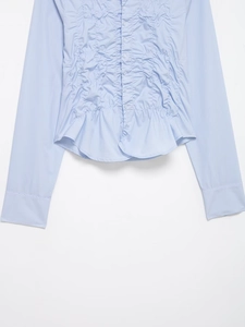 Détail d'une chemise en popeline bleu clair avec fronçage et boutons assortis