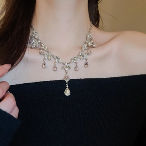 Close-up of sparkling waterdrop tassel necklace with lavender crystals on a female model