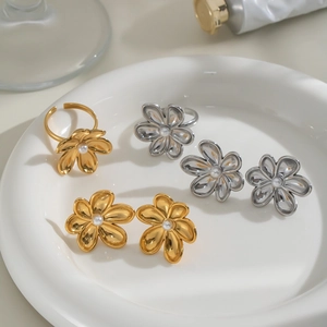 Detailed view of floral stud earrings and ring set with pearls on ceramic plate