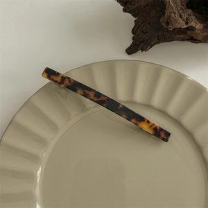 Detail view of large tortoiseshell acetate hair claw clip on a ceramic tray