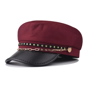 Detail of burgundy military cap with gold chain and star pattern on black leather brim