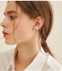 Close-up of elegant silver drop earrings with three vertically aligned crystals on model