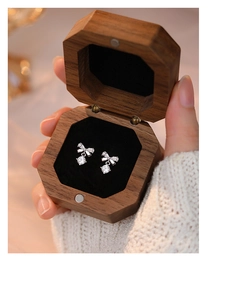 Close-up of S999 silver bow earrings with zircon in a premium walnut wood jewelry box