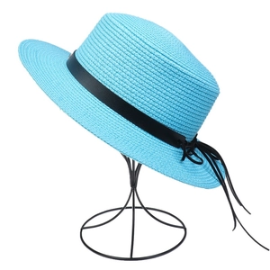 Detail of sky blue straw sun hat featuring a black leather band and bow on a display stand