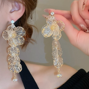 Detail of floral tassel earrings with acrylic petals, gold trim, and rhinestone inlay