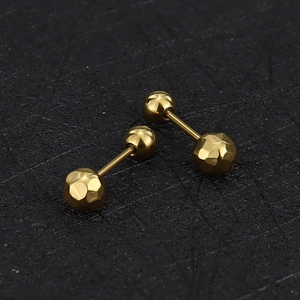 Detailed macro view of gold-plated stainless steel cartilage studs with textured geometric ball