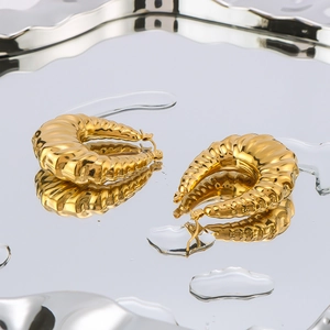 18K gold plated stainless steel croissant earrings on a reflective water drop surface