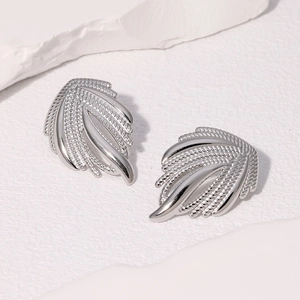 Close-up of silver wing-shaped earrings with fine texture and polished steel finish