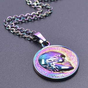 Macro shot of skull pendant in rainbow gradient finish on textured gray surface