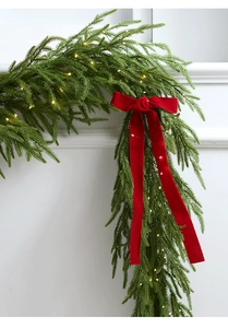 Detailed view of artificial Christmas garland with red velvet bow and LED lights