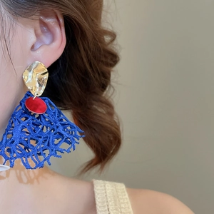 Close-up of bohemian earrings featuring gold hammer metal and blue lace fabric tassels