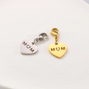 Gros plan de pendentifs cœur en or et argent avec gravure M-cœur-M et fermoirs mousqueton