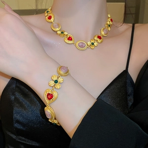 Close-up of vintage gold necklace featuring pink oval gems and red heart-shaped stones