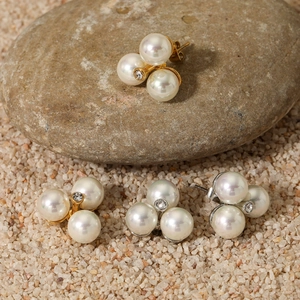 Baroque pearl flower stud earrings with central crystal on natural pebbles display