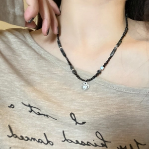 Bamboo style lock pendant necklace with black beads and silver round charm on a model