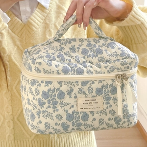 Quilted cotton cosmetic bag with blue floral patterns and reinforced handle for travel