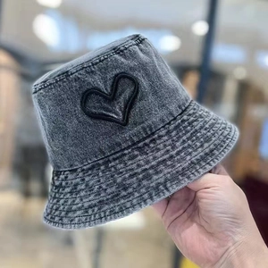 Detail of dark grey washed denim bucket hat featuring a black embroidered heart logo