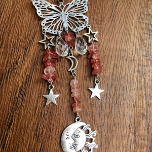 Detail of crystal suncatcher with silver butterfly, pink stones, and celestial pendants