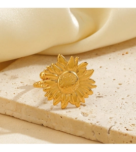 Détail d'une bague tournesol dorée avec pétales texturés sur pierre beige et tissu en soie