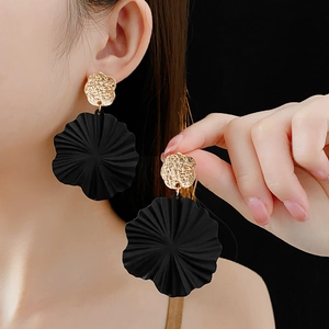 Detail view of geometric black flower earrings with hammered gold studs on a model