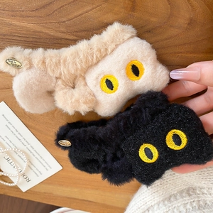 Détail de pinces à cheveux en peluche douce avec yeux brodés et petit logo en métal doré