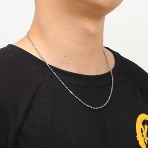 Detail of silver stainless steel cylinder and bead chain necklace on a model wearing black
