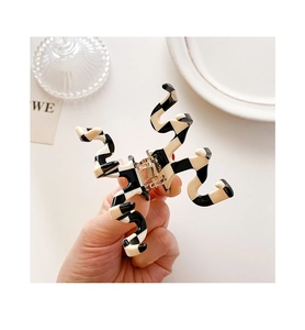 Detail shot of a small checkered resin hair claw clip with a twisted geometric design