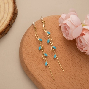 Detailed view of long leaf fringe earrings with gold metal lines and blue leaf accents