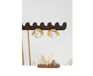 Macro shot of elegant faux pearl earrings in gold metal frame on a wooden display stand