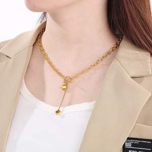 Λεπτομέρεια χρυσού κολιέ καρδιά με αλυσίδα O και κούμπωμα OT φορεμένο σε μοντέλο