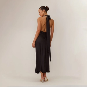 Detail view of the elegant backless design and satin texture on the black halter dress