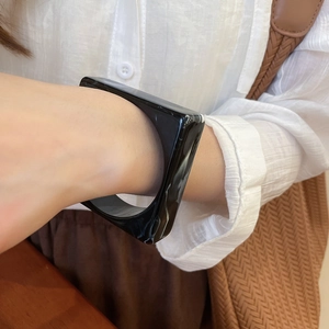 Close-up of minimalist black acrylic square thick bangle on a model wrist