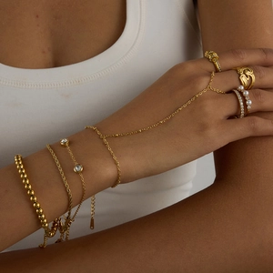 Close-up of gold titanium steel hand chain and pearl rings with zircon inlays