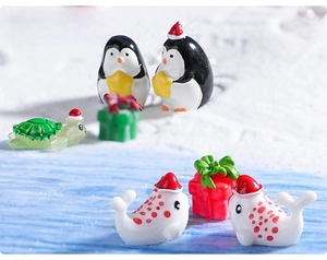Miniature Christmas resin penguin and seal figurines on a winter landscape background