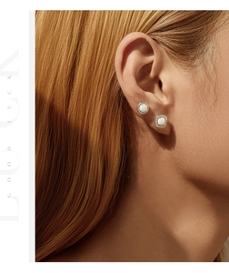 Close-up of asymmetrical S925 silver opal halo studs worn by a model in warm light