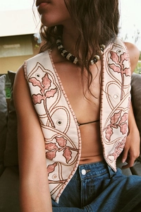 Close-up of pink and beige floral embroidery on a mirror-effect sleeveless vest
