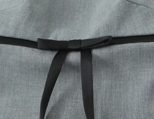 Detail of grey fabric texture featuring a black satin bow decoration on the waistline
