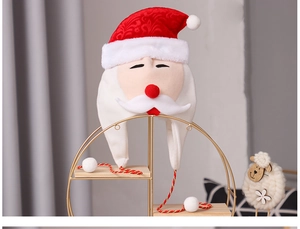Detail of soft plush Santa Claus hat with white beard and red pom-poms on a display stand