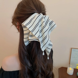 Détail d'une pince à cheveux à nœud rayé avec pendentifs perles sur cheveux attachés