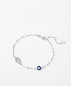 Macro shot of S925 silver bracelet featuring Hamsa hand and blue Evil Eye charm