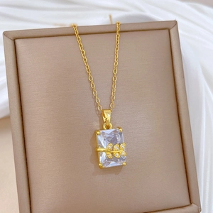 Detail of gold necklace with rectangular clear gemstone and leafy pave-set diamond accents