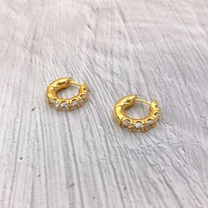 Detail of 18K gold plated hoop earrings featuring sparkling green zircon stones